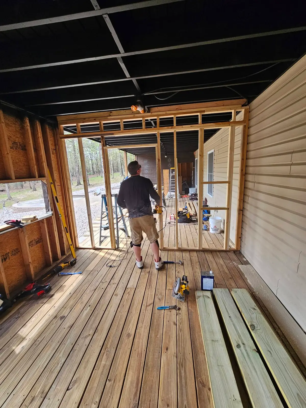 During: under-deck bay framed out in studs with the deck boards laid and the ceiling joists painted black.