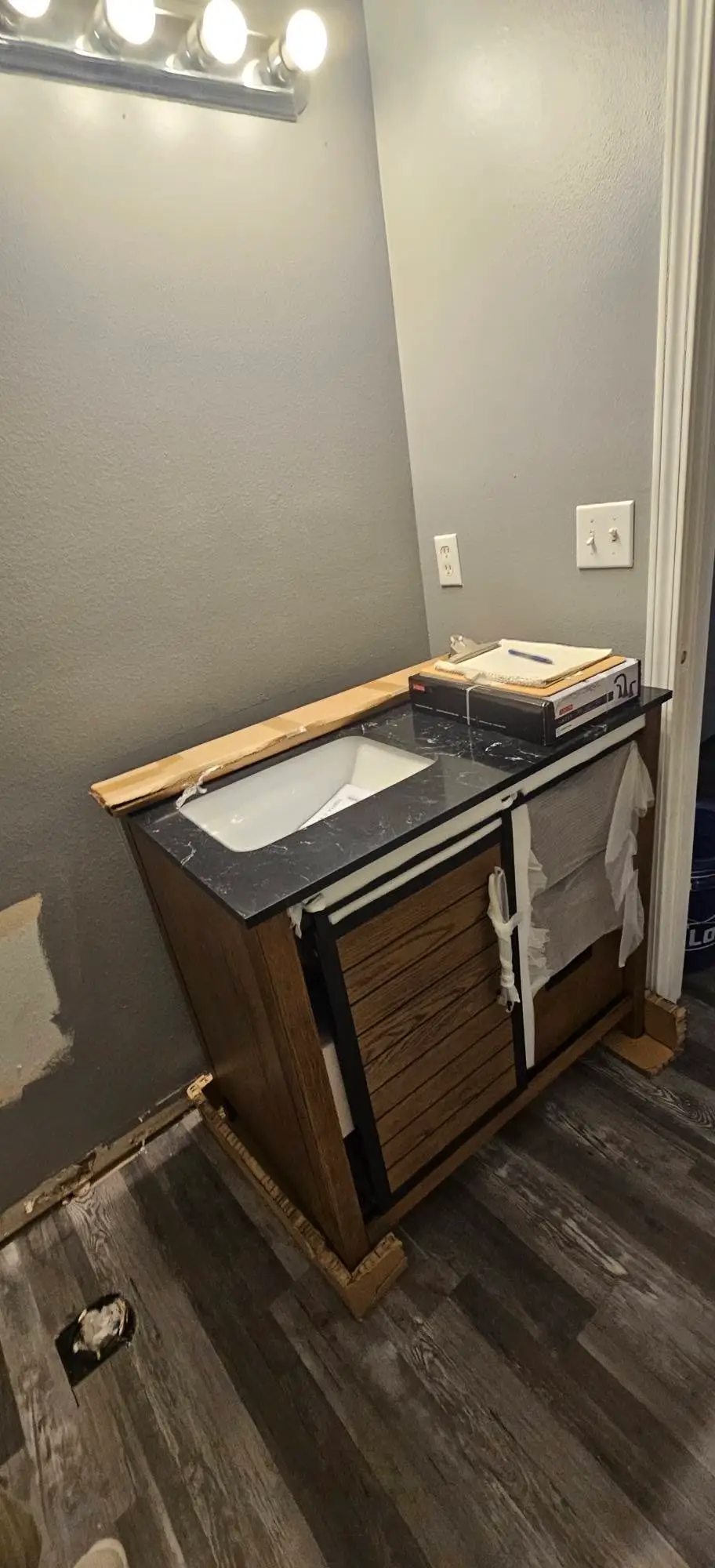 Before: vanity carcass standing loose on shims with the top unset and no plumbing connected.