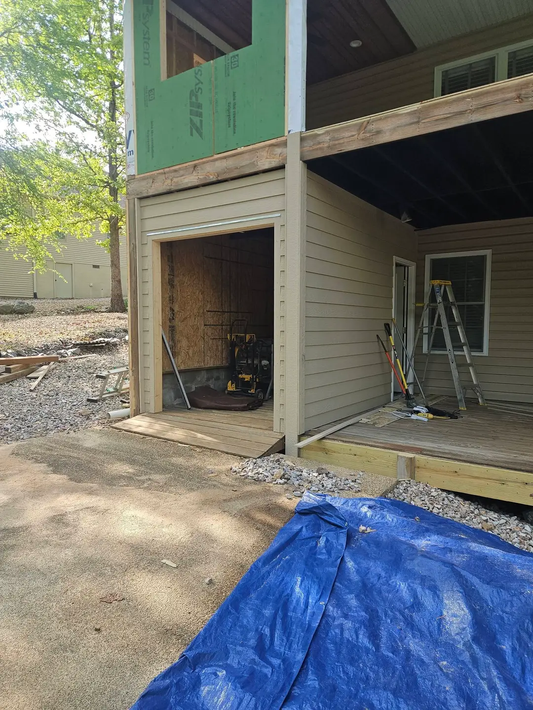 Before: open storage bay under the upper floor with bare OSB inside and ZIP sheathing still exposed above.