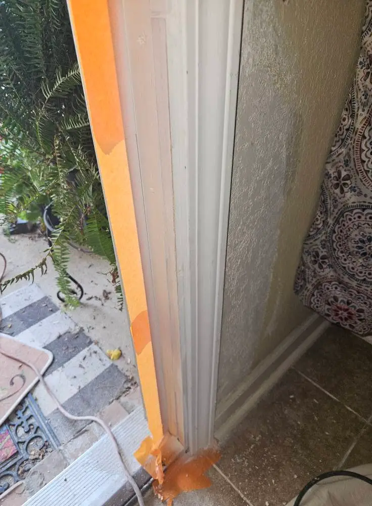After: door jamb and casing filled and painted white, with the masking tape still along the edge.