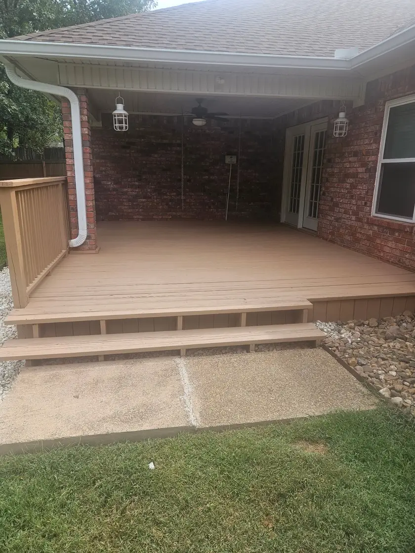 After: covered porch deck painted an even tan, with the railing section back in place and the steps repainted.
