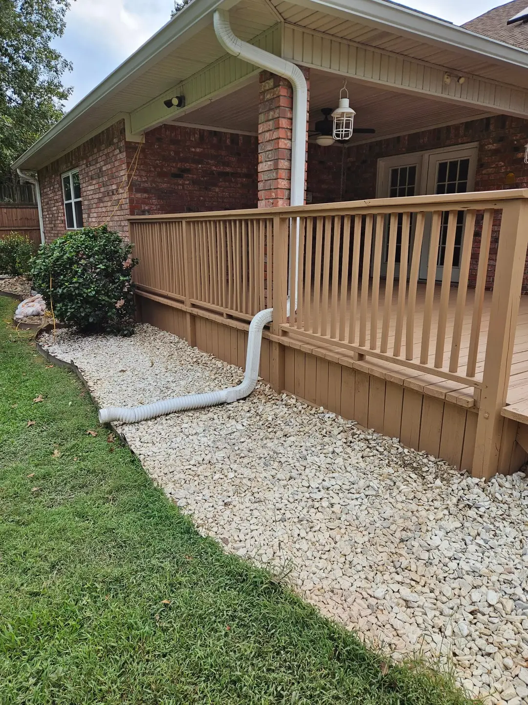 After: porch railing and skirting painted tan along the full run, over a fresh gravel drip bed.