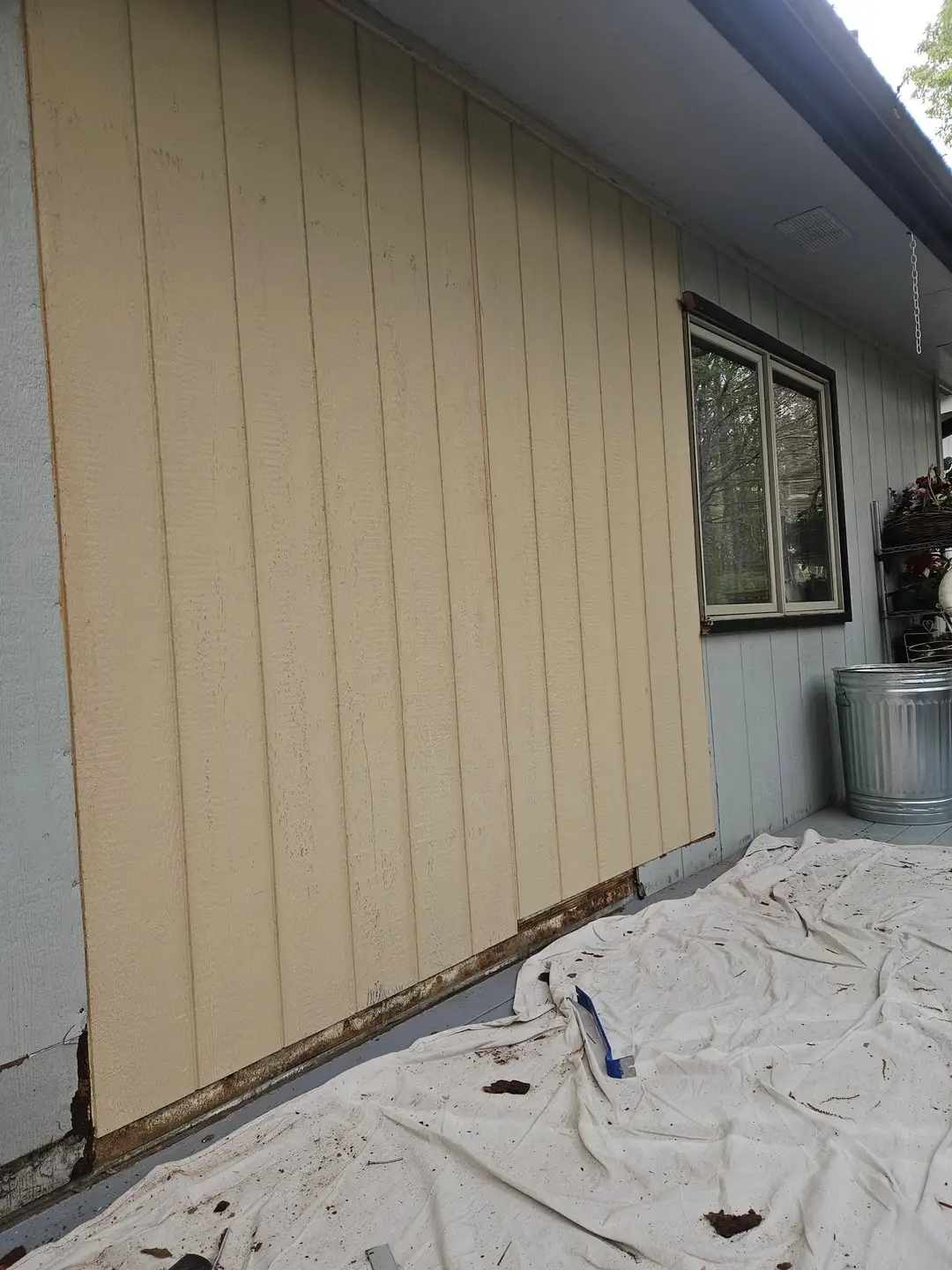 After: wall closed in with new vertical groove panels painted cream, with a drop cloth still down.