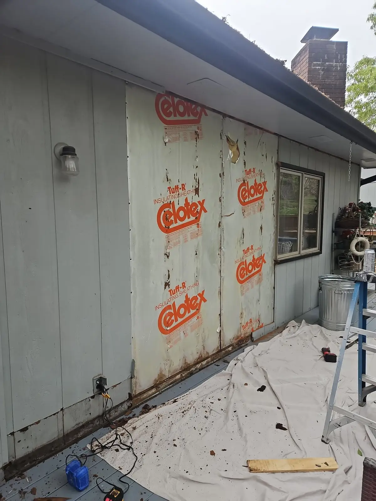 Before: two bays of foil-faced sheathing exposed where the siding came off, with rot along the bottom plate.