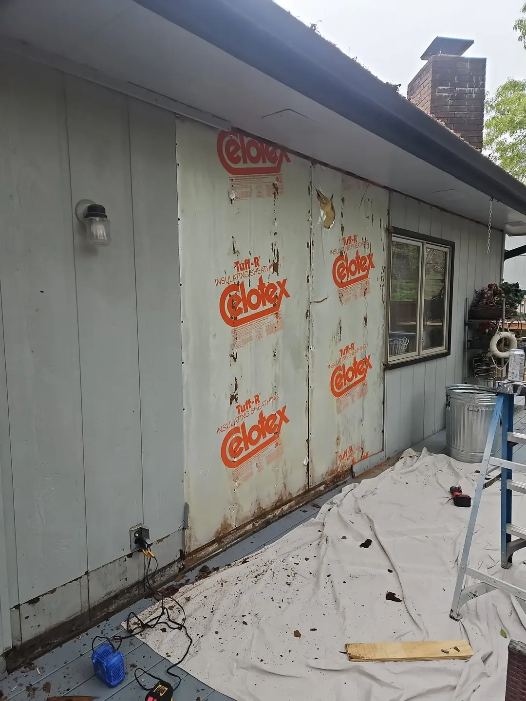 Before: two bays of foil-faced sheathing exposed where the siding came off, with rot along the bottom plate.