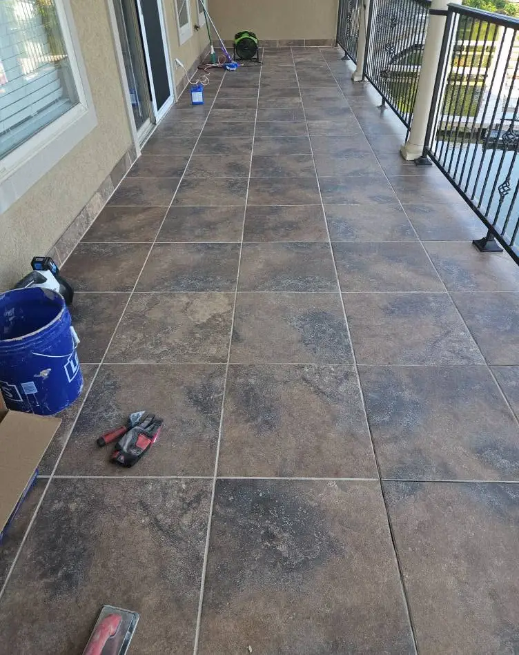 After: balcony tile regrouted in clean light gray down the full run to the railing.