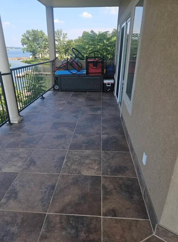 After: full balcony run regrouted, the tile swept clean from the glass door to the railing.