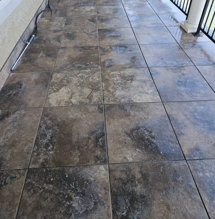 Before: balcony tile with the grout joints soiled dark, wet from the first pass of cleaning.