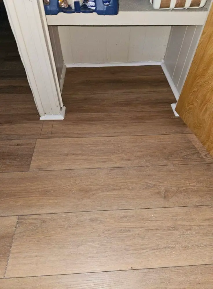 After: light oak LVP running under a built-in bench, with a wood transition at the doorway.