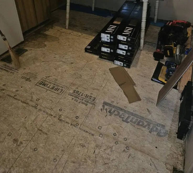 Before: bare AdvanTech subfloor across the kitchen with boxes of LVP stacked and waiting.