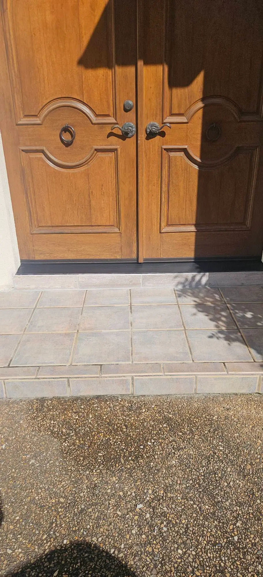 After: tiled entry step laid in gray porcelain with a bullnose edge, under closed arched doors.