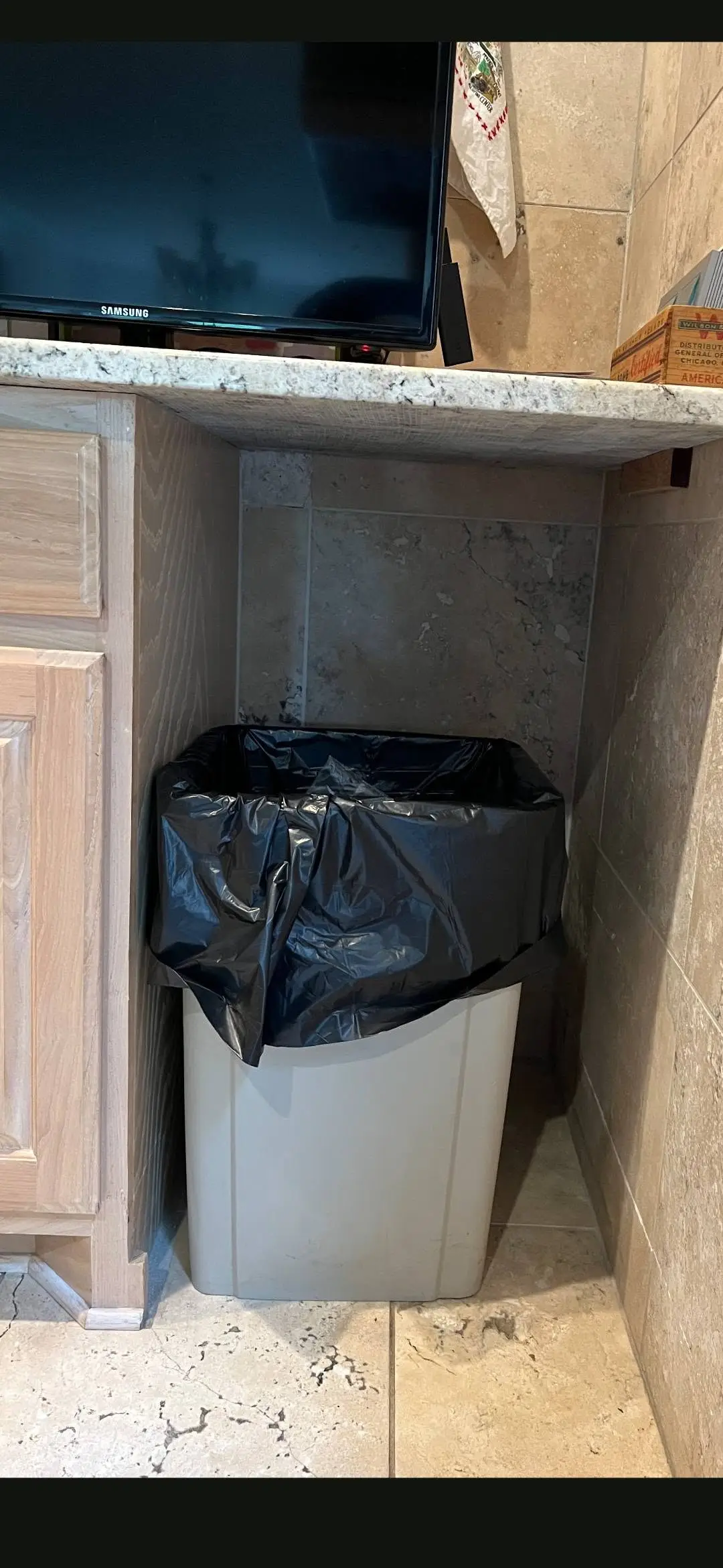 Before: open gap in the cabinet run holding a loose plastic trash can with a bag over the rim.