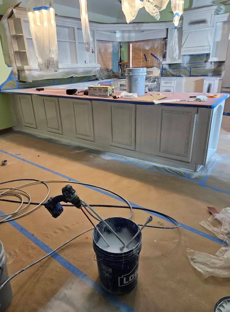 After: peninsula and wall cabinets sprayed light gray, with the counter still papered.