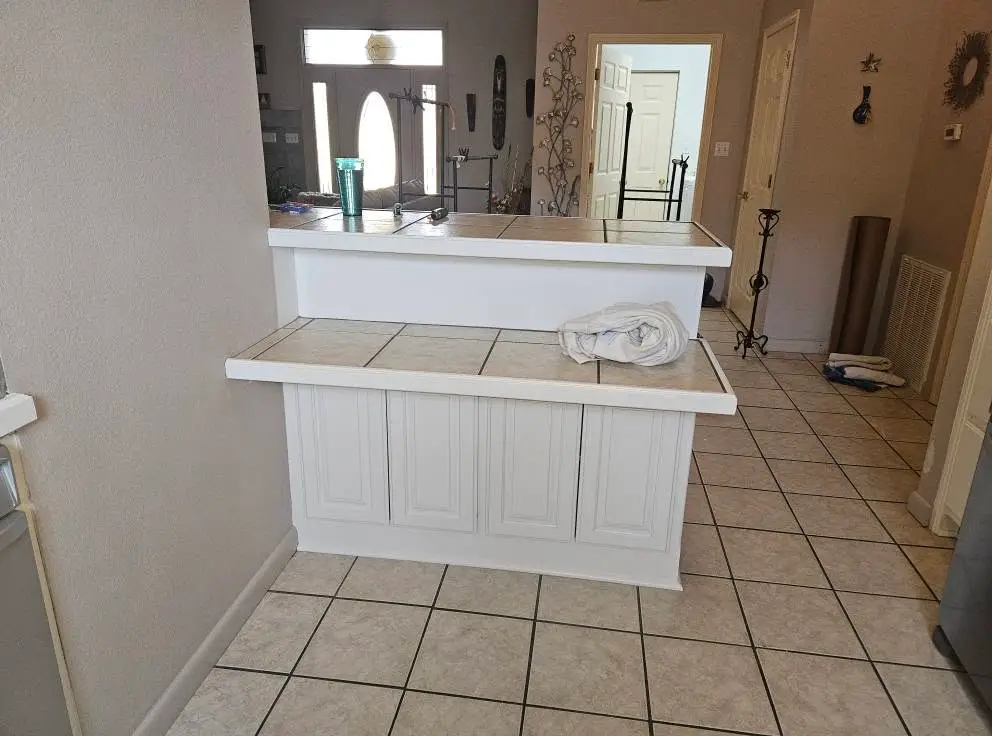 After: raised tile-topped pass-through bar with the cabinet panels below it painted white.