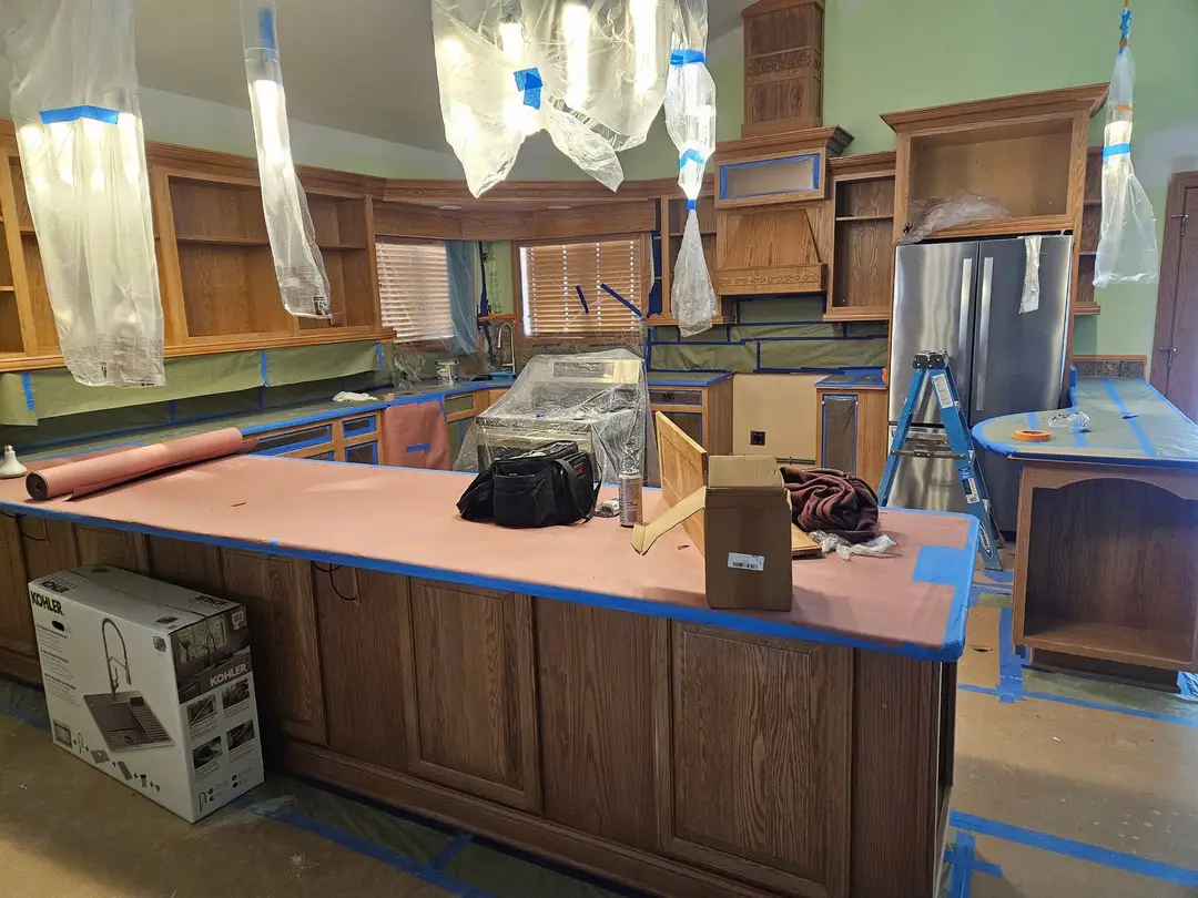 Before: oak peninsula and wall cabinets in place, counters papered and the openings masked in plastic.