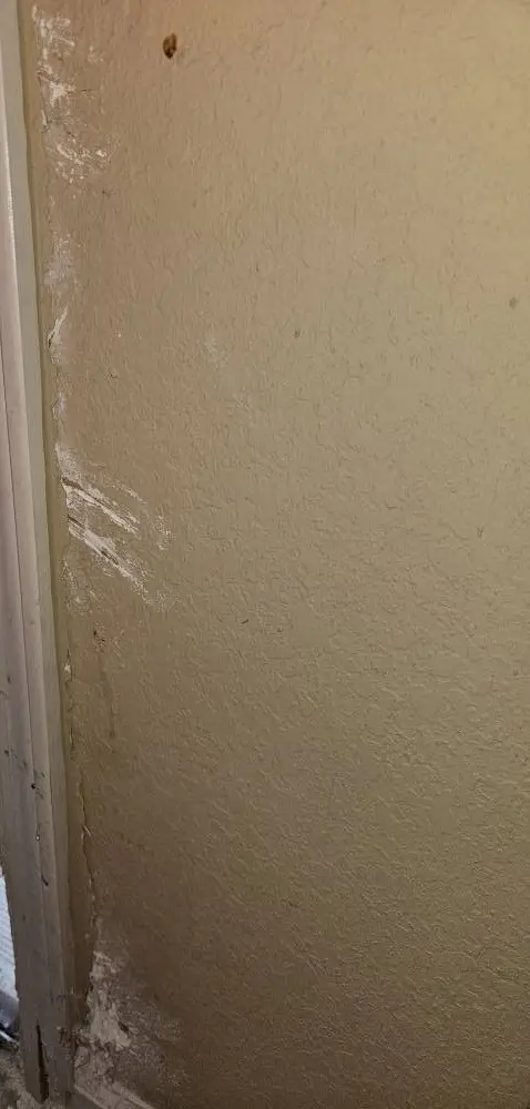 Before: drywall corner beside an exterior door scraped through the paint and gouged to the paper.