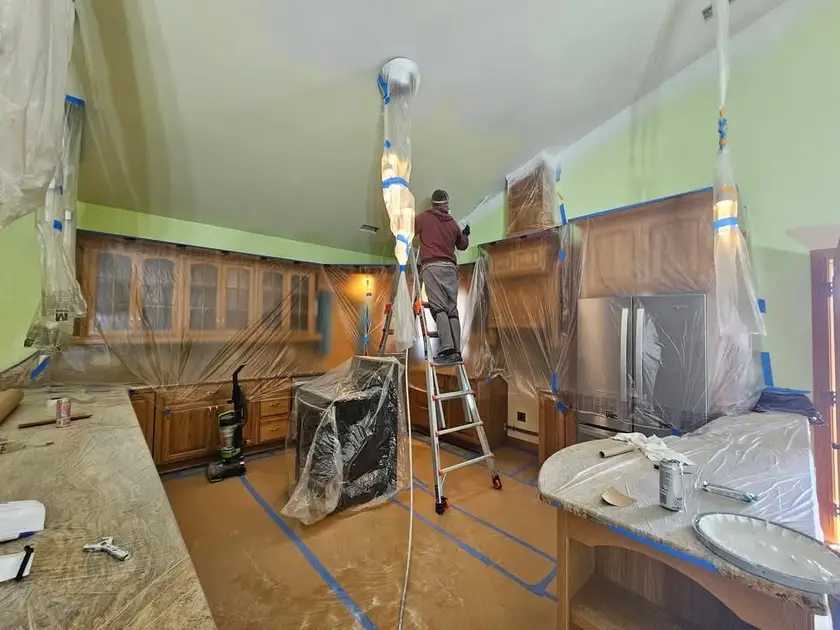 During: kitchen ceiling sprayed white with the oak cabinets and the refrigerator wrapped in plastic.