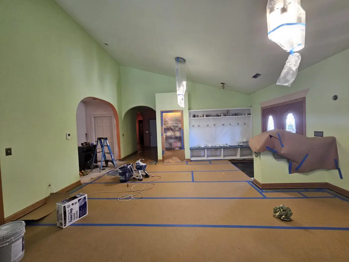 During: great room taped off at the arched openings and the built-in, with the floor covered in rosin paper.