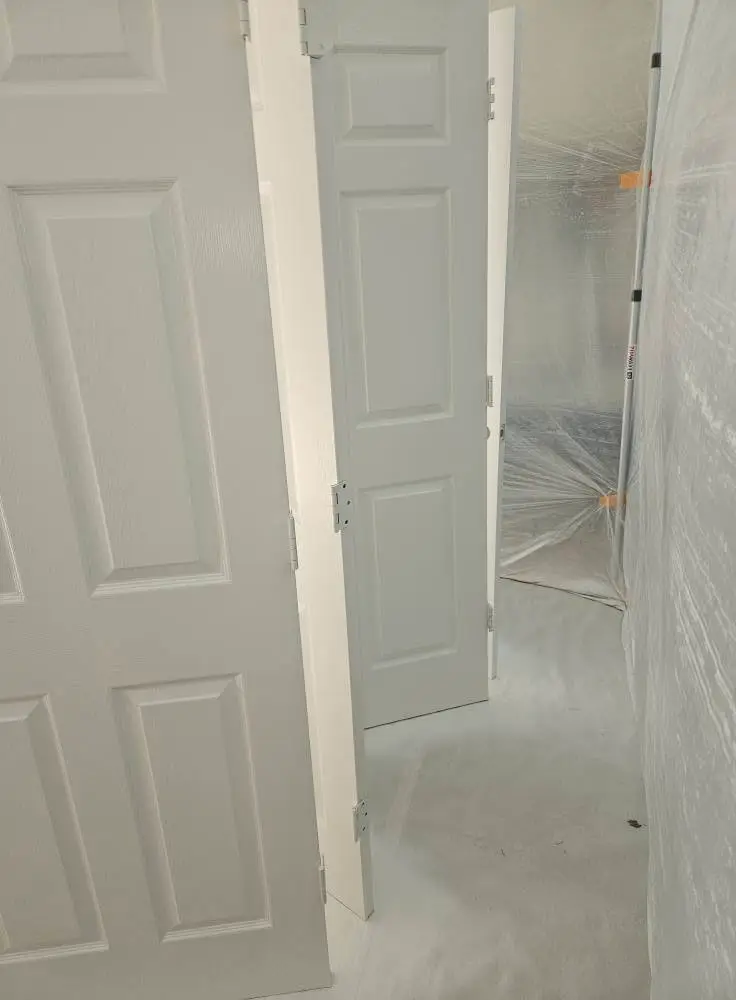 After: six-panel interior doors and casings finished in soft white, with the hallway still sheeted in plastic.