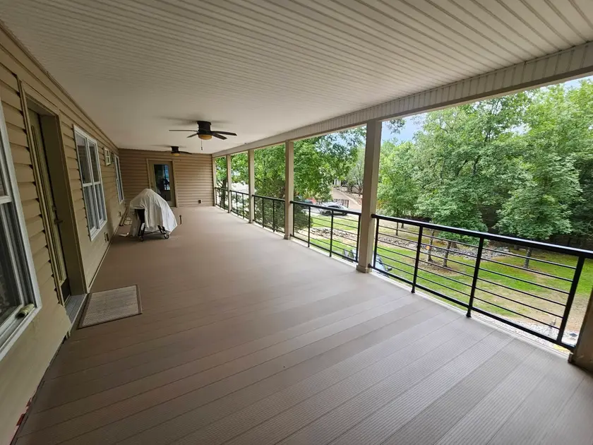 After: finished composite porch running the full elevation, with black cable railing along the open side.