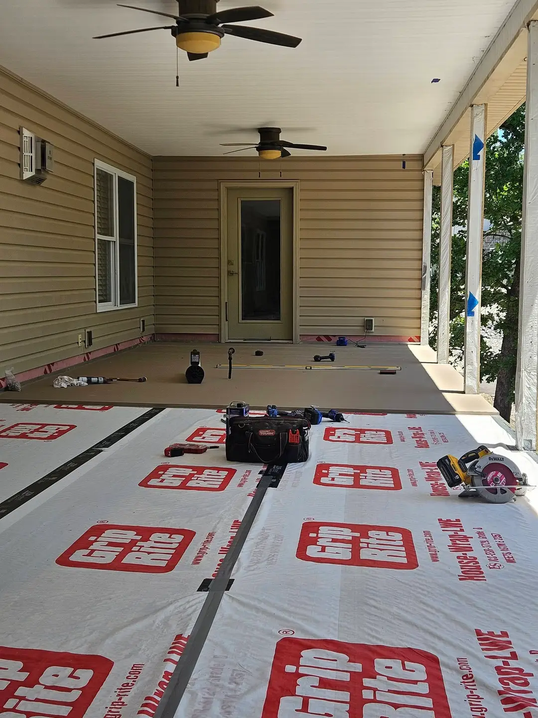 Before: covered porch floor covered in synthetic underlayment over bare framing, ready for composite boards.