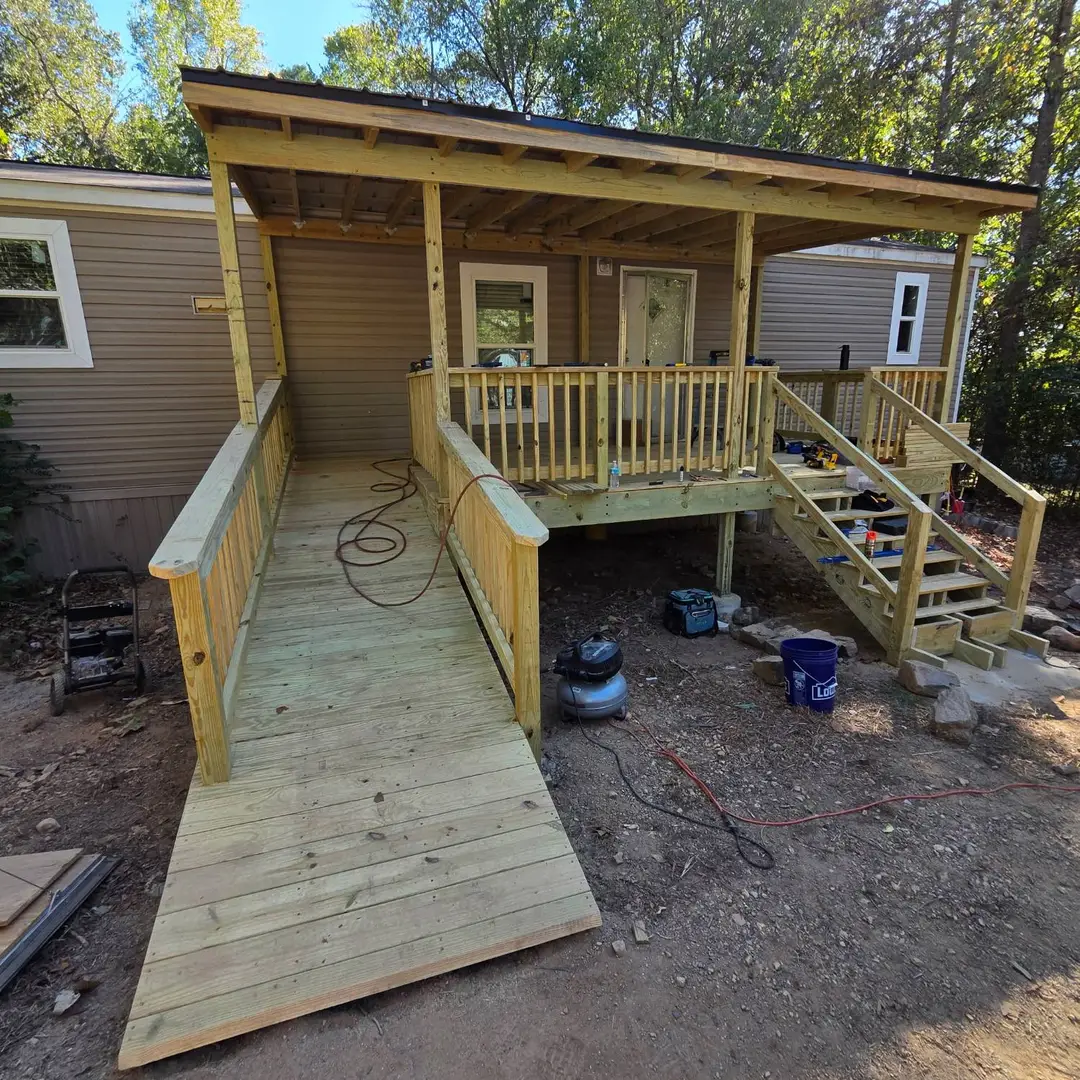 After: a covered porch built in new treated lumber, with handrails along a long ramp and a stair, under a metal roof.