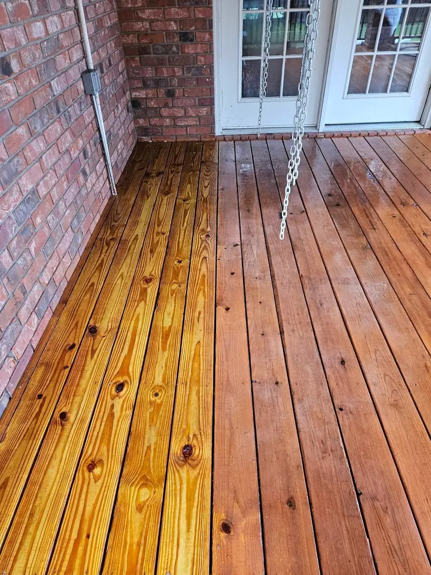 After: porch boards stained warm amber, the grain reading clean right up to the brick wall.