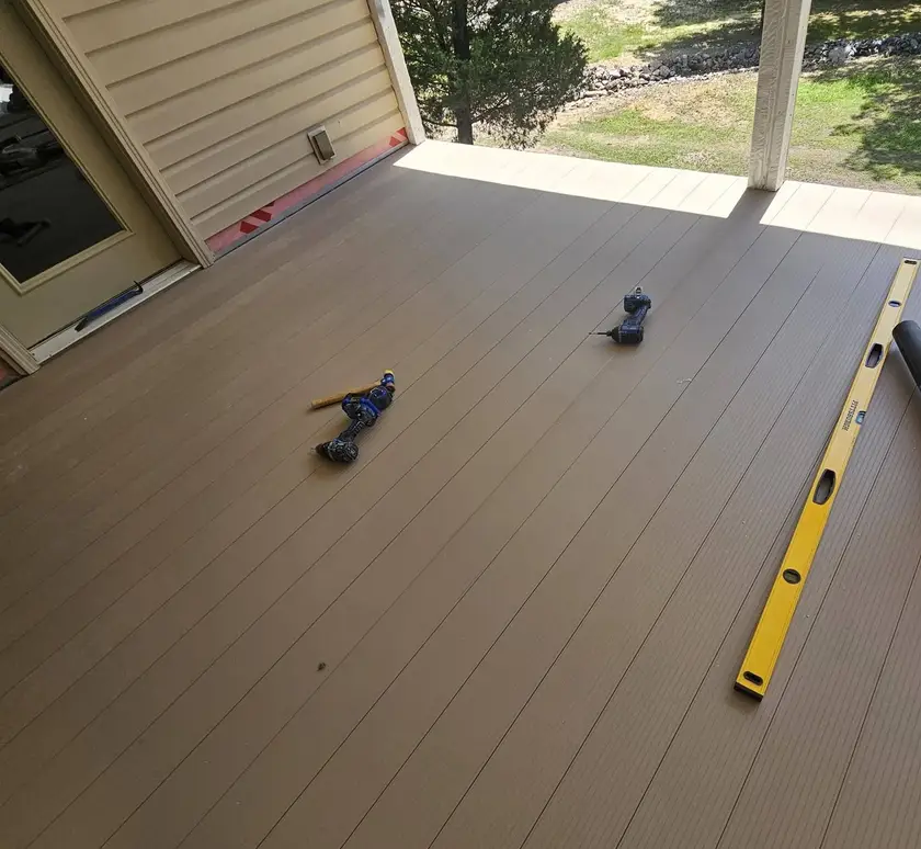 During: composite deck boards run out square to the post, with the level and the driver still on the boards.