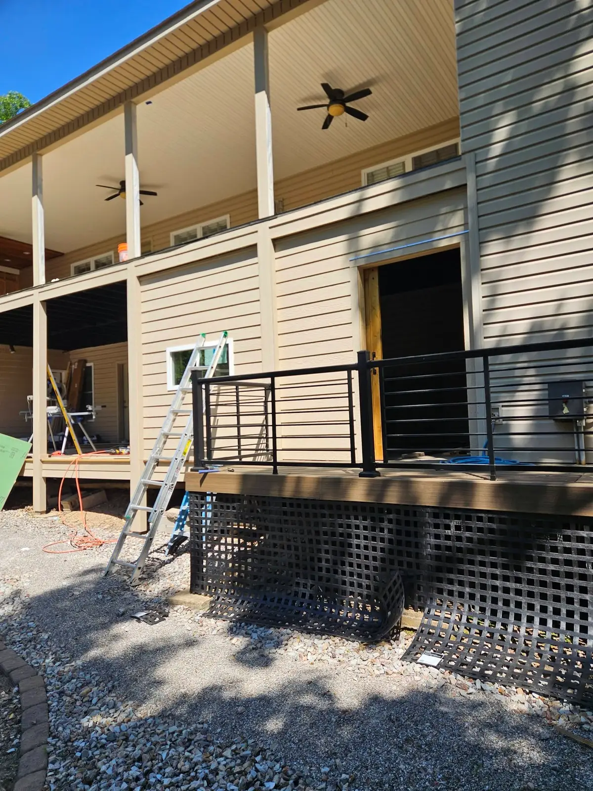 During: composite deck boards run out to the black horizontal railing, with black lattice skirting fitted below.
