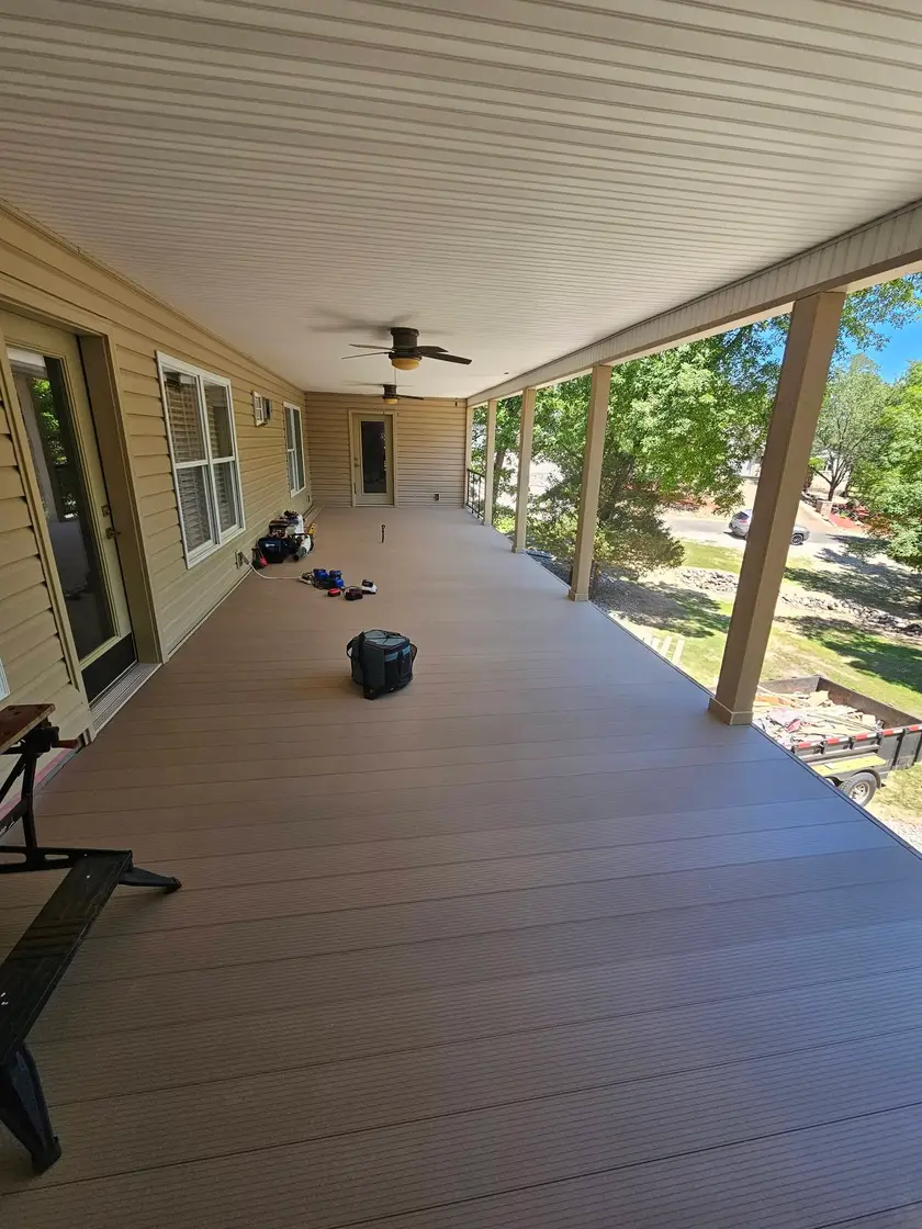 During: long covered porch decked in composite boards, with the posts set and the railing still to come.
