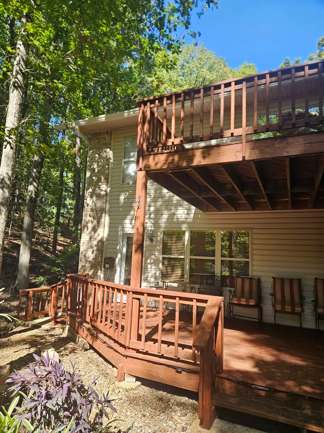 After: two-level deck carrying an even dark stain, with the upper balcony railing finished to match.