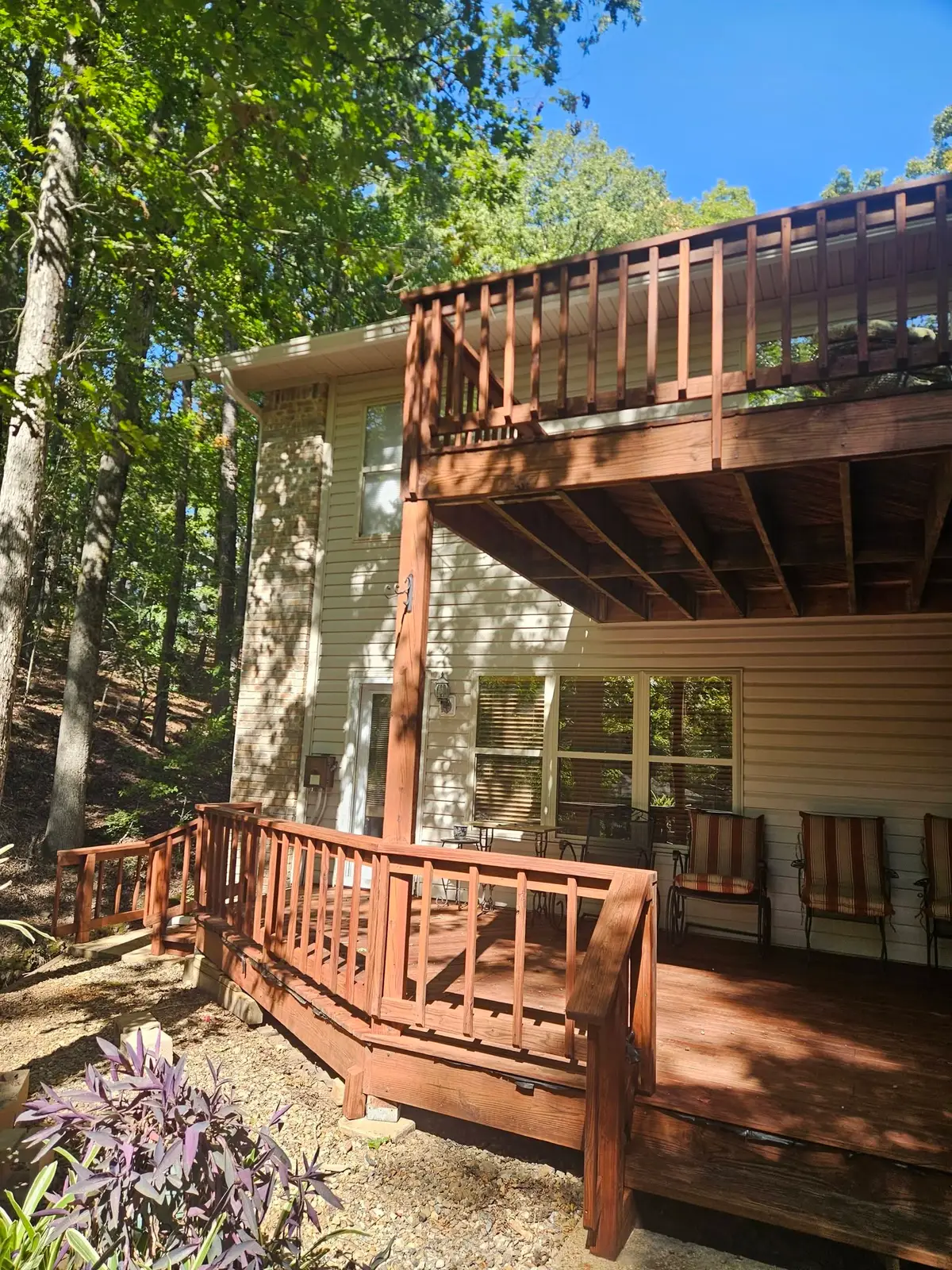 After: two-level deck carrying an even dark stain, with the upper balcony railing finished to match.