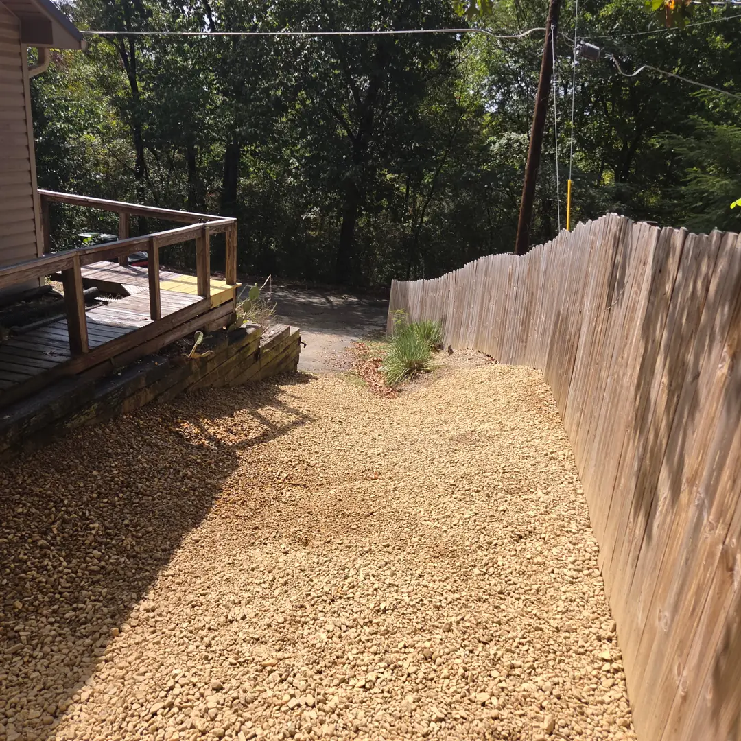 After: the same yard graded and covered in washed river gravel, carried from the deck out to the fence line.