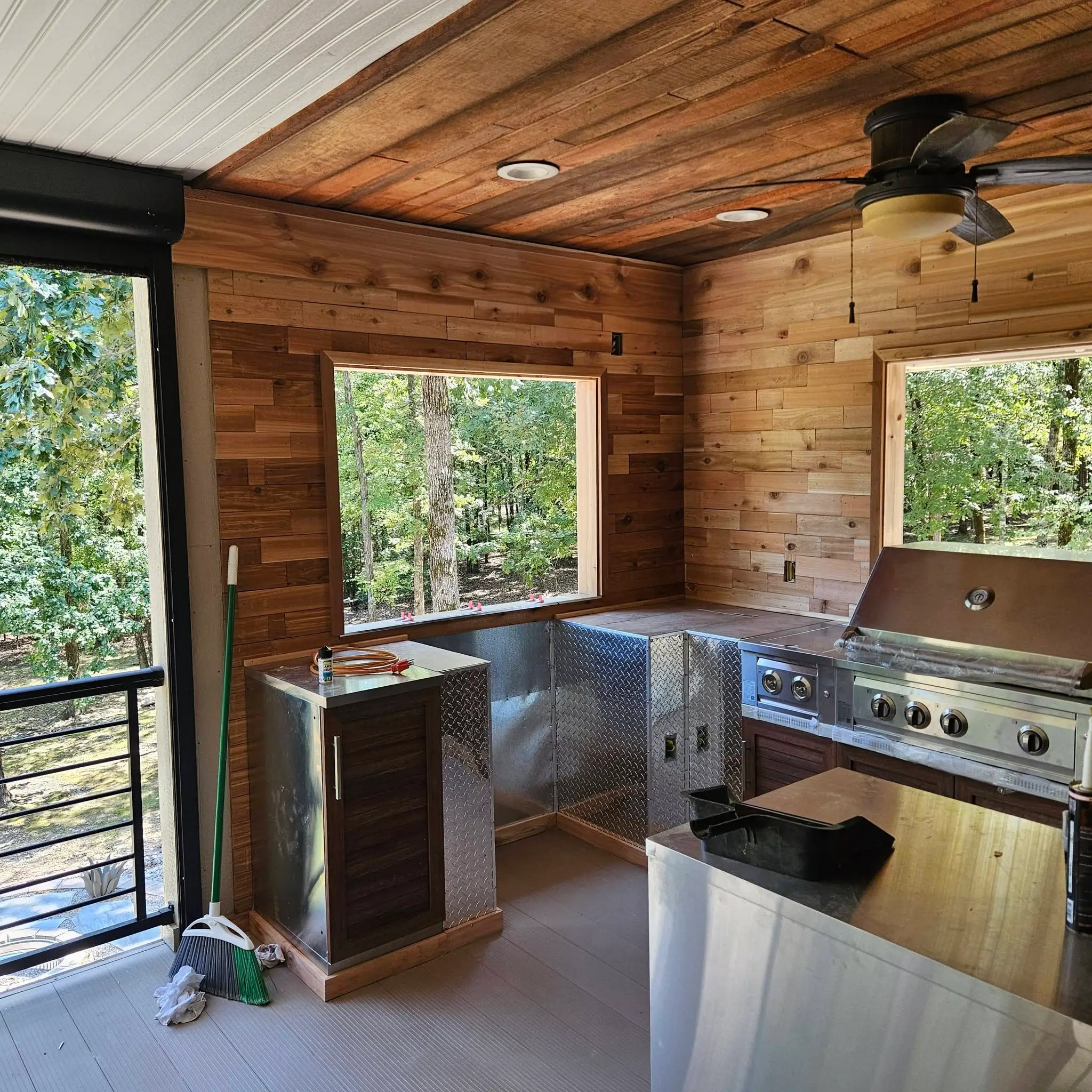 After: cedar-lined porch room with a stainless counter run, a built-in grill and a bar sink at the window.