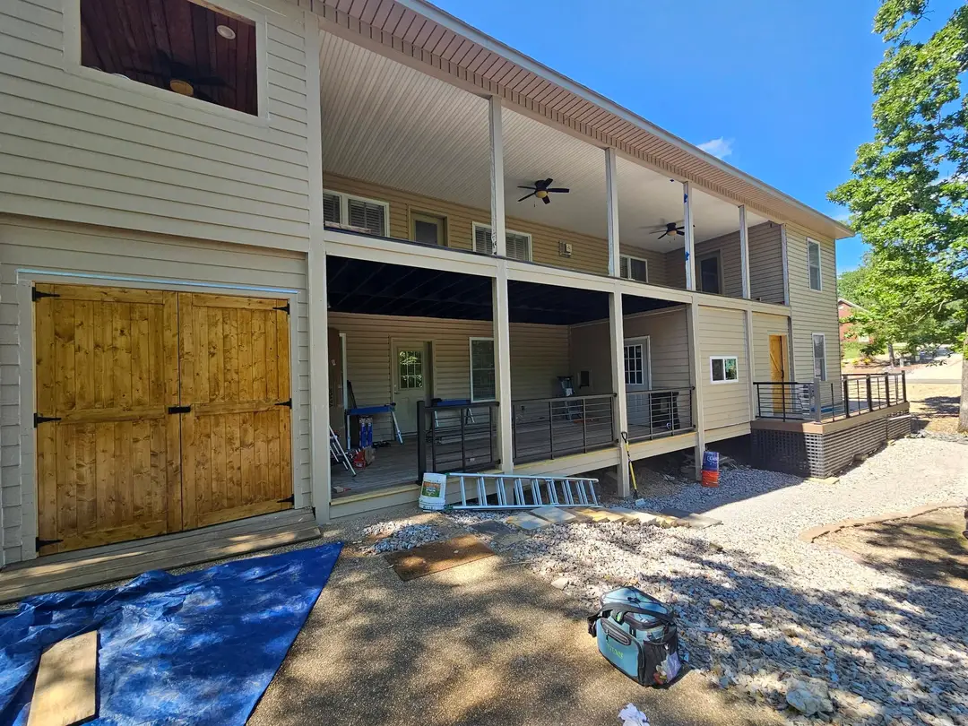 After: rear elevation finished in siding, stained barn doors, composite decking and black cable railing.